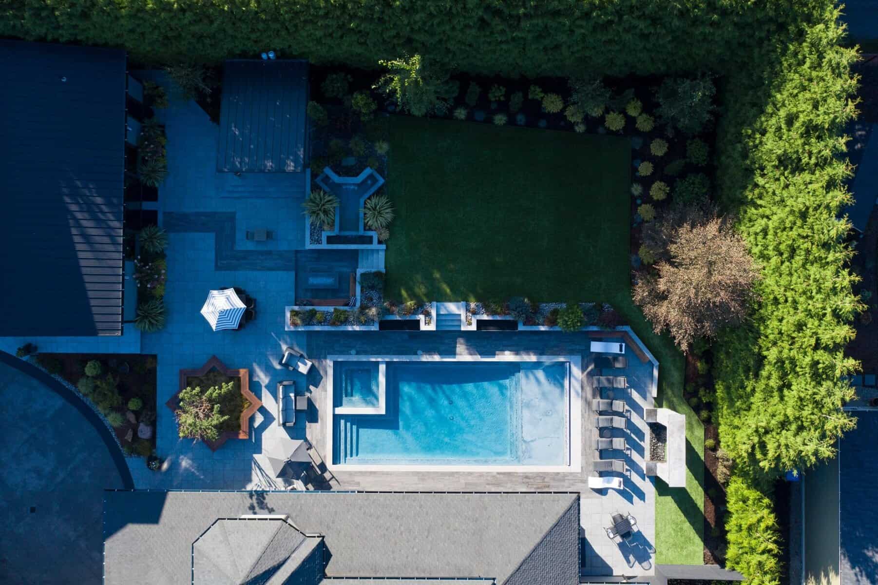 Drone view of porcelain paver pool surround with outdoor kitchen and water wall, Tacoma